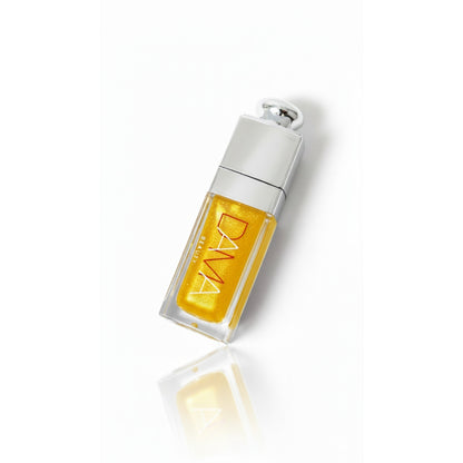 Yellow lip oil with silver cap on a white background